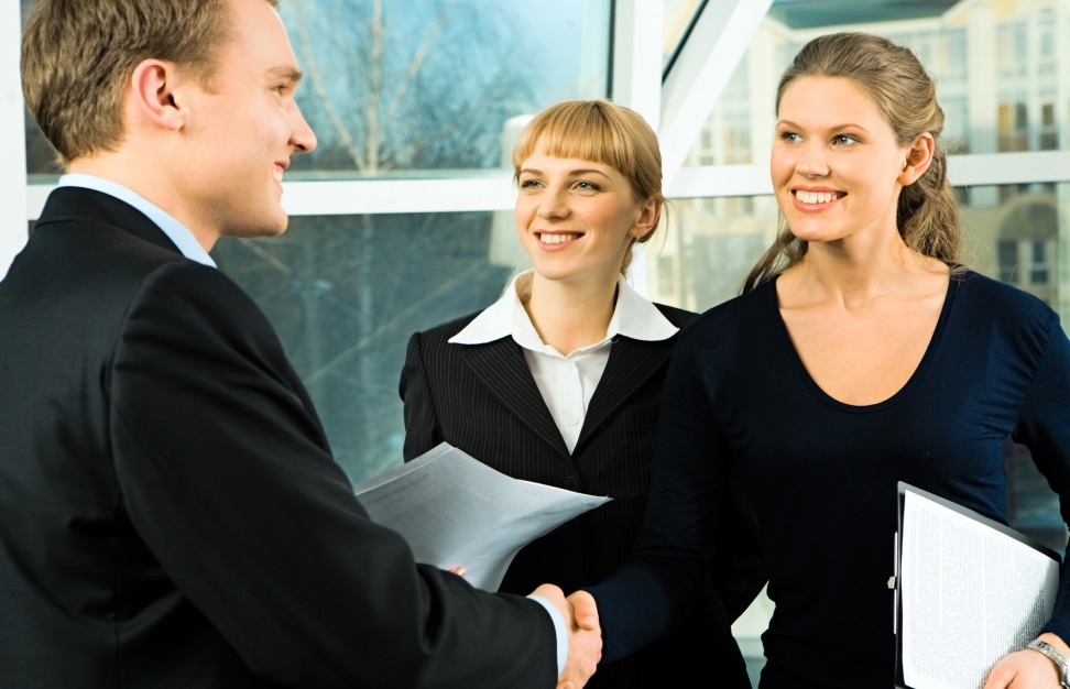 Two Business Women Shaking Hands with a Business Man